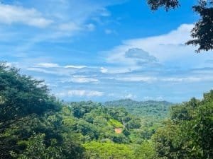 Scenic view of lush green land with partial ocean view and blue sky in Dominical.