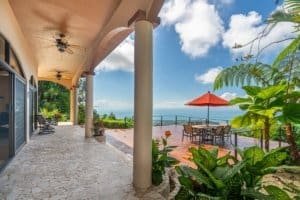 Ocean view from Mediterranean-inspired villa with patio and lush greenery.