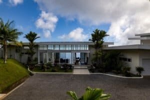 Modern estate entrance with palm trees and ocean view in Dominical, Costa Rica.