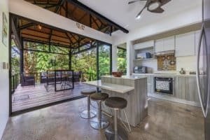 Open-concept kitchen with outdoor deck and lush greenery in Dominical.