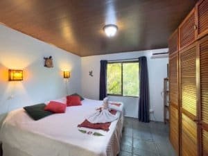 Comfortable bedroom with bed, window view, and wooden closet in Dominical.