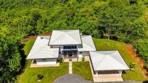 A modern luxury home surrounded by lush greenery and scenic views.