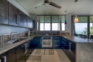 Contemporary kitchen with dark cabinets and panoramic jungle views in Dominical.