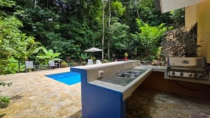 Outdoor kitchen with pool and lush tropical garden in Dominical.