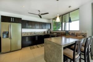 Contemporary kitchen with dark cabinets, large window, and island in Dominical.