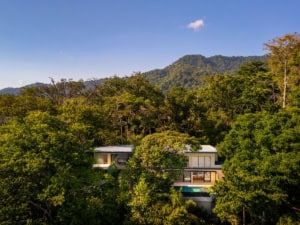 Modern luxury home nestled in lush Costa Rican jungle with mountain backdrop.