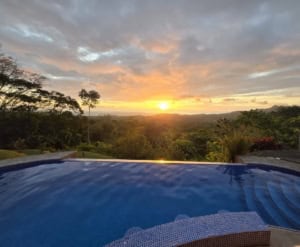 Infinity pool overlooking lush forest and sunset in Dominical, Costa Rica.