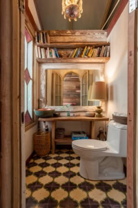 Rustic bathroom with wooden shelves, books, and a toilet in Dominical, Costa Rica.