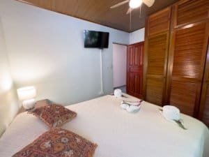 Bedroom with large bed, wooden closet, TV, and decorative pillows in Dominical.