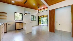 Bright, open-concept living space in Dominical with large windows and wooden ceiling.