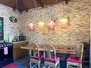 Interior of a Costa Rican kitchen with stone walls, wooden cabinets, and pendant lighting.