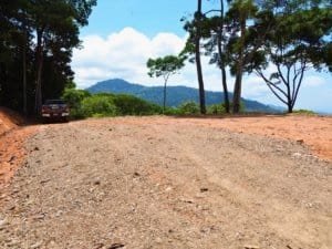 Gated land with ocean view, trees, and mountain background in Dominical.