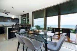 Interior of a modern jungle home with ocean view and glass doors.