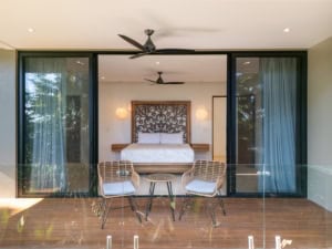 Modern bedroom with ocean view balcony, stylish decor, and tropical surroundings.