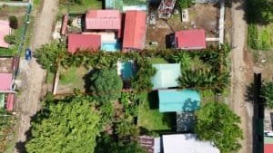 Aerial view of Dominical land with a house, pool, and lush greenery.