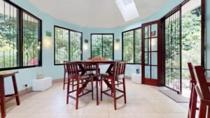 Sunroom with large windows overlooking lush garden in Dominical.