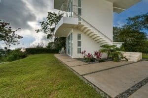 Contemporary house with white exterior, staircase, and lush garden in Costa Rica.