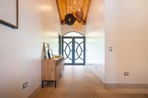 Elegant entryway of a jungle home with wooden ceiling and decorative lighting.