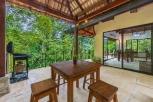 Balcony with wooden table and stools overlooking lush jungle canopy in Dominical.