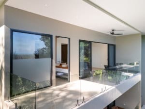 Modern tropical home with ocean view, balcony, and outdoor seating area.