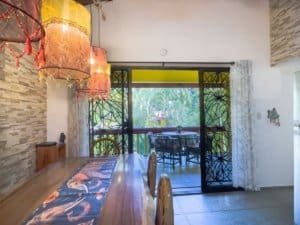 Costa Rican dining area with balcony, tropical view, and colorful decor.