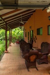 Covered porch with wicker furniture and lush tropical garden view.