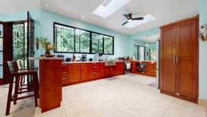 Bright kitchen with large windows, wooden cabinets, and modern appliances in Dominical.