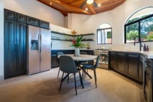 Contemporary kitchen with black cabinets, stainless steel fridge, and wooden ceiling in Dominical.