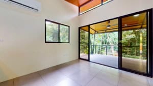 Bright living room with large glass doors and balcony overlooking nature.