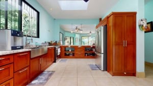 Bright kitchen with wooden cabinets, stainless steel appliances, and large windows.