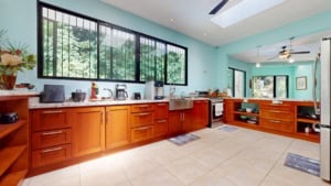 Bright kitchen with large windows, wooden cabinets, and modern appliances in Costa Rica.