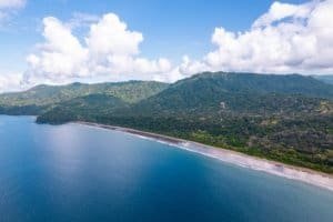 Scenic view of Dominical coastline, mountains, and ocean under blue sky.