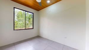 Empty room with large window and wooden ceiling in Dominical property.