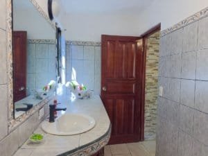 Bathroom with sink, mirror, and tiled walls in Dominical Costa Rica.