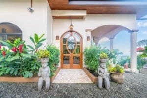 Entrance of a Mediterranean-inspired villa with lush plants and statues in Dominical.