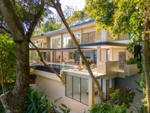 Modern tropical home with ocean view, large windows, and lush greenery.