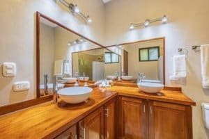 Bright bathroom with double vessel sinks and wooden vanity in tropical villa.