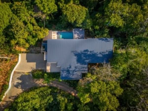 Aerial view of a tropical home with pool surrounded by lush forest in Dominical.