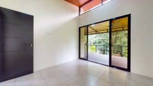 Bright interior of a Dominical property with large glass doors and balcony view.