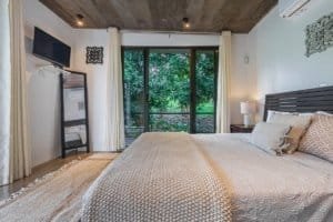Bright bedroom with large window overlooking lush greenery in Dominical.
