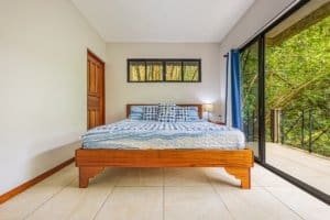 Bedroom with large glass door opening to jungle balcony in Dominical.