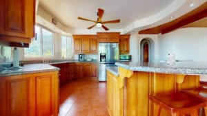 Bright kitchen with large windows, wooden cabinets, and granite countertops.
