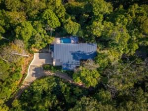 Aerial view of a luxury home with pool surrounded by lush forest in Dominical.