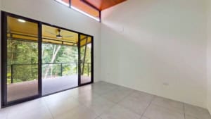 Bright living room with large glass doors leading to balcony and green scenery.
