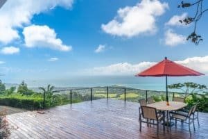Deck with table and umbrella overlooking ocean and lush landscape in Dominical.