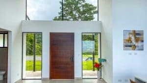Contemporary home entrance with wooden door and glass side panels in Dominical.