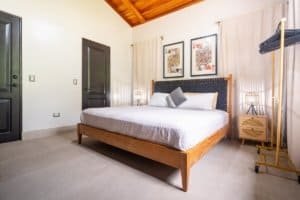 Bright bedroom with wooden bed, artwork, and tropical decor in Dominical.