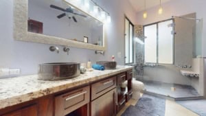 Contemporary bathroom with dual vessel sinks, large mirror, and glass shower enclosure.