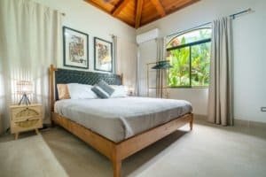 Bright bedroom with jungle view, modern decor, and high wooden ceiling.