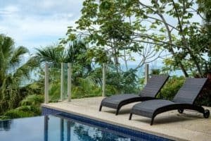 Poolside lounge chairs overlooking lush jungle and ocean view in Dominical.
